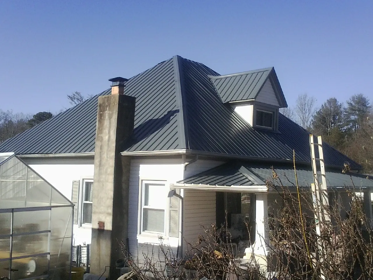 Dark blue standing seam metal roof on a white farmhouse with dormer — Slate & Tile Roof Repair by Roofing Brothers in Petersburg